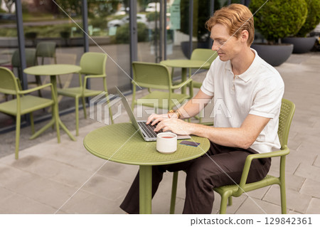Remote worker focused on screen typing fast outdoors surrounded 129842361