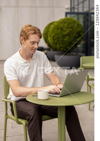 Young Caucasian male entering text on keyboard checking information on screen Young Caucasian male entering text on keyboard checking information on screen 129842364