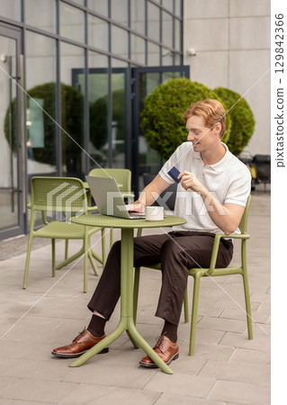 Digital nomad typing on computer validating payment using debit card 129842366