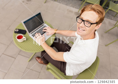 Self-employed man writing message reviewing dashboard scrolling page Self-employed man writing message reviewing dashboard scrolling page 129842385