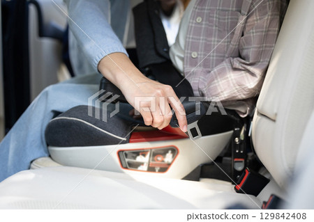 Mom fixing safety belt to her kid while traveling by car 129842408