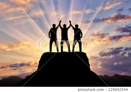 Silhouette of happy three climbers on the top of the mountain 129842544
