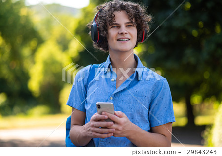 Waist up of a curly-haired teen wearing headphones Waist up of a curly-haired teen wearing headphones 129843243