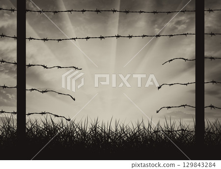 Silhouette of a broken border fence with barbed wire 129843284