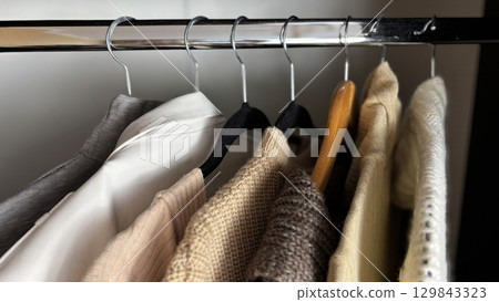 Neatly hung womens wardrobe on hangers in closet, organized autumn and winter fashion, warm knitted sweaters, seasonal clothing minimalistic organization, stylish clothes storage, womens fashion Neatly hung womens wardrobe on hangers in closet, organized autumn and winter fashion, warm knitted sweaters, seasonal clothing minimalistic organization, stylish clothes storage, womens fashion 129843323