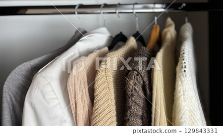 Neatly hung womens wardrobe on hangers in closet, organized autumn and winter fashion, warm knitted sweaters, seasonal clothing minimalistic organization, stylish clothes storage, womens fashion Neatly hung womens wardrobe on hangers in closet, organized autumn and winter fashion, warm knitted sweaters, seasonal clothing minimalistic organization, stylish clothes storage, womens fashion 129843331