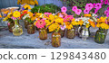 A Beautiful Floral Arrangement Showcased in Colorful and Charming Jars and Vases 129843480