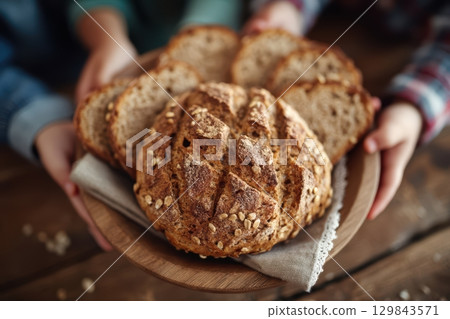A Freshly Baked Rustic Bread Loaf Resting on a Wooden Table, Ready to Enjoy with Family 129843571