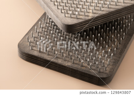 Wooden boards sadhu with nails for practicing yoga on beige background. Healthy stimulation of blood flow in legs. Yoga Tool. Close up. Wooden boards sadhu with nails for practicing yoga on beige background. Healthy stimulation of blood flow in legs. Yoga Tool. Close up. 129843807