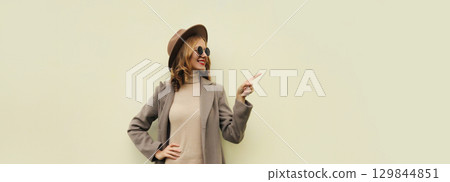 Beautiful happy woman pointing her finger to the side looking away on white background, copy space 129844851