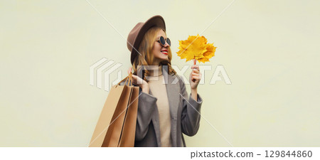 Autumn portrait of beautiful happy woman with shopping bag, stylish girl holding yellow maple leaves Autumn portrait of beautiful happy woman with shopping bag, stylish girl holding yellow maple leaves 129844860