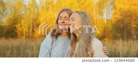 Happy two women, smiling mature mother and adult daughter hugging in autumn park 129844880