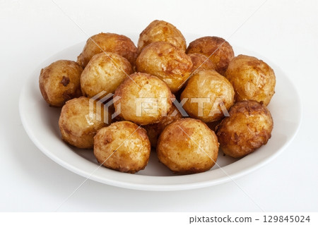 Delicious and crispy Golden Fried Potato Balls served elegantly on a pristine White Plate 129845024