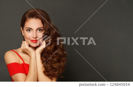 Cute woman with long hair and make-up on black background. Gorgeous woman with curly hairstyle 129845054
