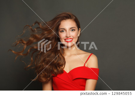 Gorgeous fashion model woman with shiny skin, wavy hairstyle and red lips makeup on black background 129845055