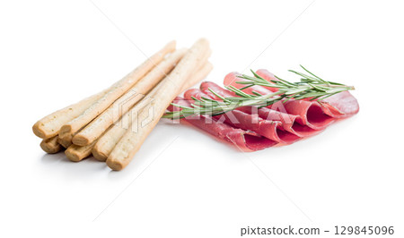 Slices of smoked bresaola and grissini sticks isolated on white background. Slices of smoked bresaola and grissini sticks isolated on white background. 129845096