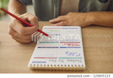 Close up photo of business man hands writing to do list in his notepad sitting at the table. 129845123