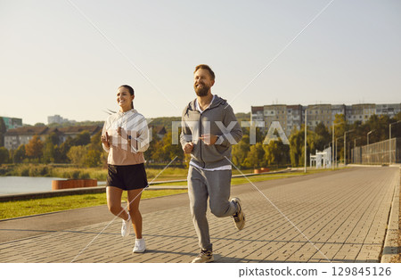 Young happy couple running in the park having sport workout together outdoors. Young happy couple running in the park having sport workout together outdoors. 129845126