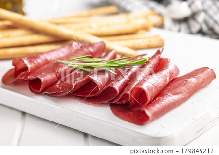 Slices of smoked bresaola on white table. 129845212