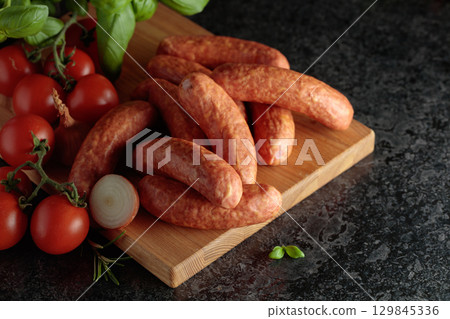 Sausages with basil, onion, rosemary, and tomatoes. 129845336