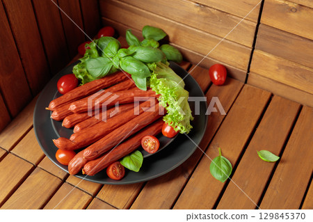 Thin smoked Polish sausages on a black plate. Thin smoked Polish sausages on a black plate. 129845370