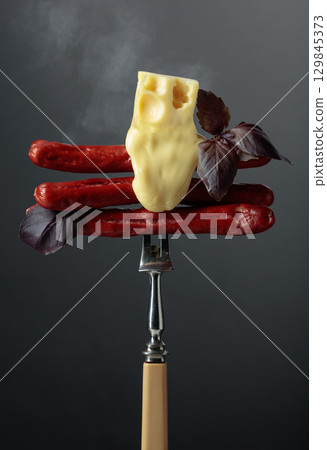 Grilled thin sausages with cheese and basil. 129845373