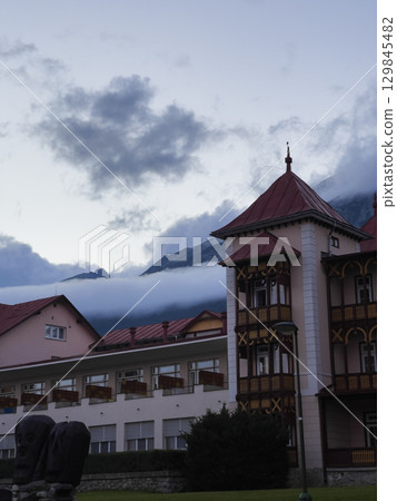 Vysoke Tatry, Slovakia - August 4, 2025: View of the Tatra Mountains and houses from the city streets in cloudy weather. Vysoke Tatry, Slovakia - August 4, 2025: View of the Tatra Mountains and houses from the city streets in cloudy weather. 129845482