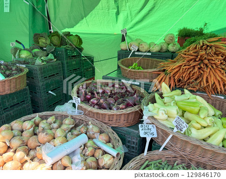 Baskets overflowing with vibrant carrots, onions, peppers, and cabbages create an inviting display of fresh produce at a local farmers market 129846170