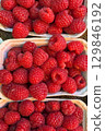 Cardboard punnets overflowing with ripe, vibrant red raspberries create a colorful and tempting display at a farmers market, showcasing the abundance of fresh, locally sourced produce 129846192