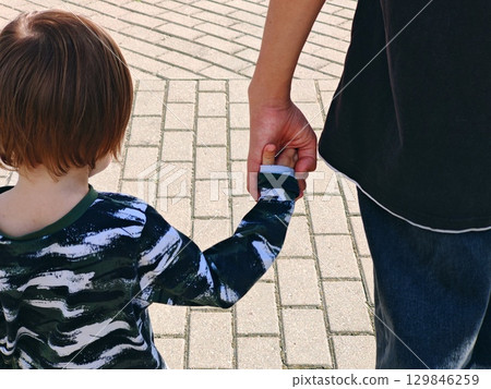 An adult holds a child's hand by the hand. Family concept. Childhood, parenting. Two brothers. 129846259