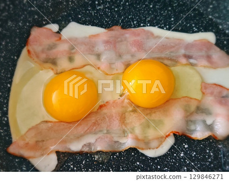 Scrambled eggs and bacon on frying pan. scrambled eggs with bacon are fried in a pan Scrambled eggs and bacon on frying pan. scrambled eggs with bacon are fried in a pan 129846271