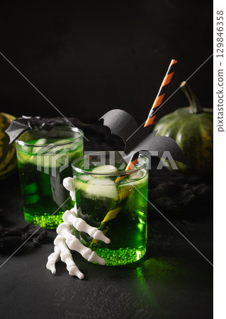 Green Halloween cocktail garnish fun black bat and skeleton hand. Festive drink , spooky setting, featuring eerie elements and playful holiday decor. Green Halloween cocktail garnish fun black bat and skeleton hand. Festive drink , spooky setting, featuring eerie elements and playful holiday decor. 129846358