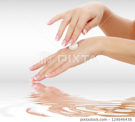 Female hands with a moisturiser on light grey background Female hands with a moisturiser on light grey background 129846436