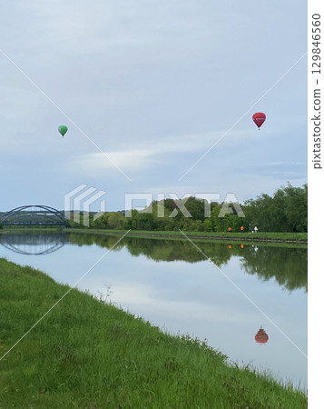 Hot air balloons flying over a water canal 129846560
