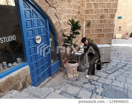 A woman is standing in front of a blue door with a sign that says Studio A woman is standing in front of a blue door with a sign that says Studio 129846601
