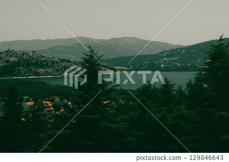 A beautiful view of a lake surrounded by green hills and trees under a calm sky. A serene landscape featuring a lake nestled amidst rolling hills and lush evergreen trees, a tranquil picturesque scene A beautiful view of a lake surrounded by green hills and trees under a calm sky. A serene landscape featuring a lake nestled amidst rolling hills and lush evergreen trees, a tranquil picturesque scene 129846643