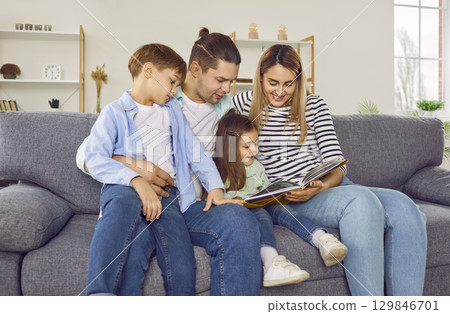 Happy family of four reading book at home 129846701