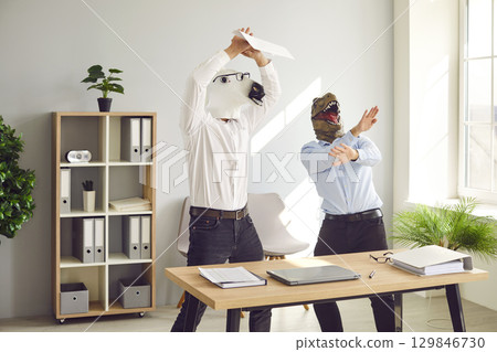 Office workers in horse and dinosaur masks dancing and having party at work before weekend 129846730