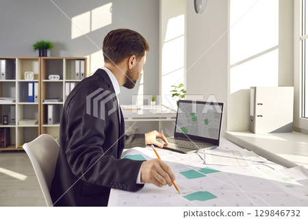 Cadastral surveyor is working with cadastral city maps and using a laptop computer 129846732