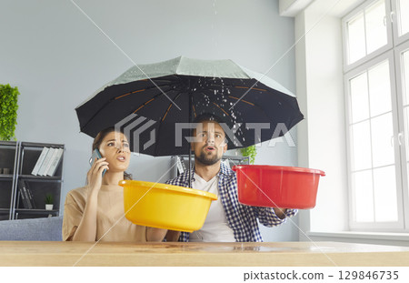 Young stressed couple calling to repair services due to roof leaks at home 129846735