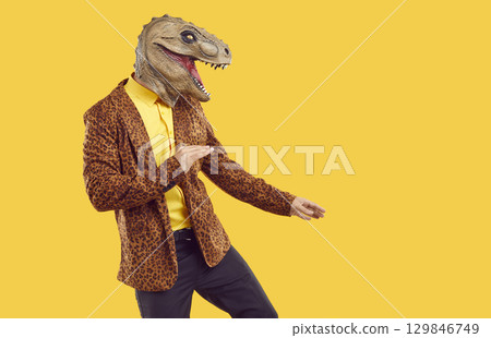 Funny guy in leopard jacket and dinosaur mask dancing on yellow copy space background 129846749