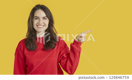 Smiling woman indicates at blank copy space, shows place for your advertisement or promotional text 129846759