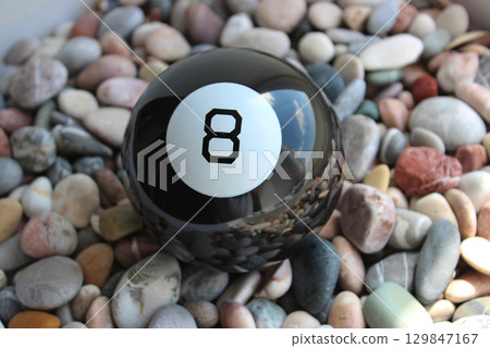 Black Billiard Ball Number Eight Lying On A Colored Smooth Pebbles Top View 129847167