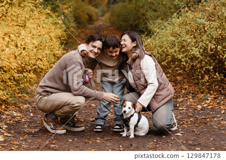 Happy family of three with dog in autumn park Happy family of three with dog in autumn park 129847178