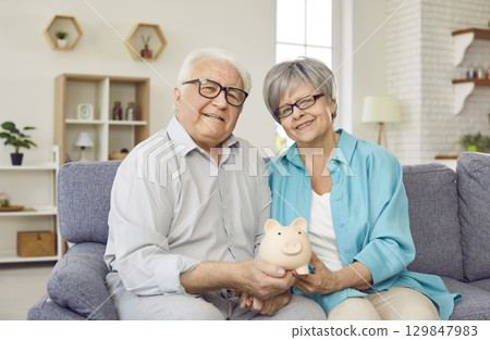 Portrait of happy senior married couple saving their family budget and saving for future. Portrait of happy senior married couple saving their family budget and saving for future. 129847983