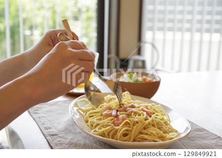 Hands of a woman eating delicious pasta Hands of a woman eating delicious pasta 129849921