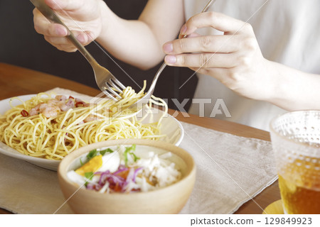 Hands of a woman eating delicious pasta Hands of a woman eating delicious pasta 129849923