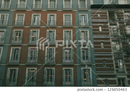 An old building facade with multiple windows and balconies in an urban setting. Facade of a building with windows and balconies. Architectural detail. European style architecture. Building exterior. 129850463