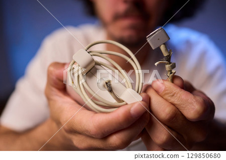 Carefully Repairing a Damaged Charging Cable with Skillful Hands for Best Results and Safety 129850680