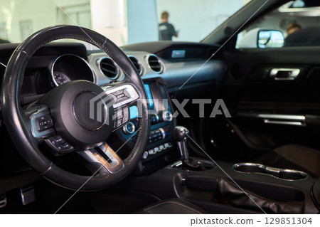 Closeup of a modern car steering wheel with control buttons for technology and convenience 129851304